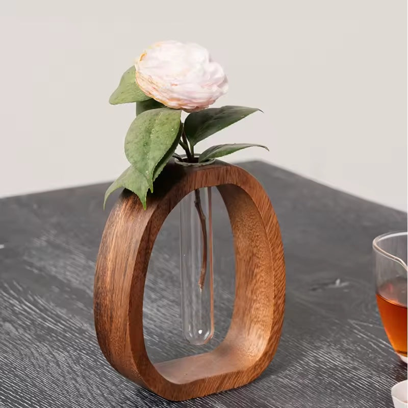 Mini-Glasvase mit Holzhalter und heller Blüte
