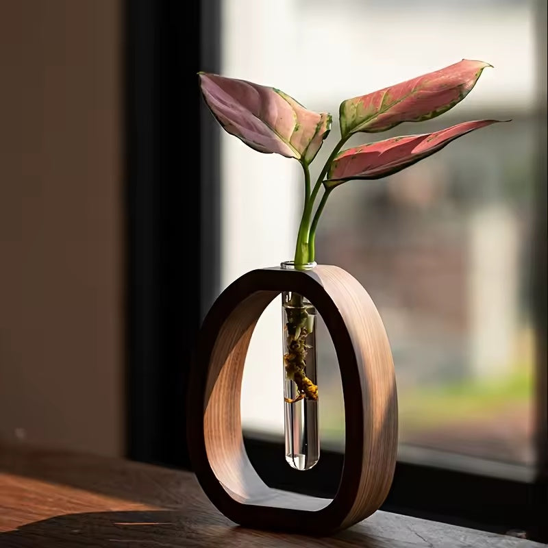 Walnussfarbener Holzhalter mit Glasvase und rosa Blättern am Fenster